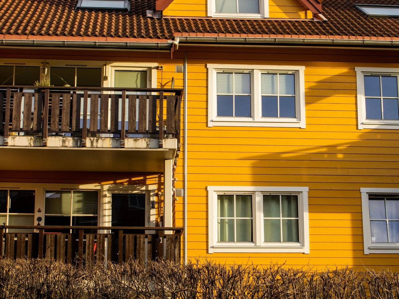 Gul norsk trebygning med hvite vindusrammer i lavt vintersollys